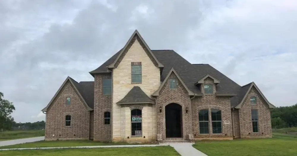 Front of a brick and stone two-storey house under an overcast sky.